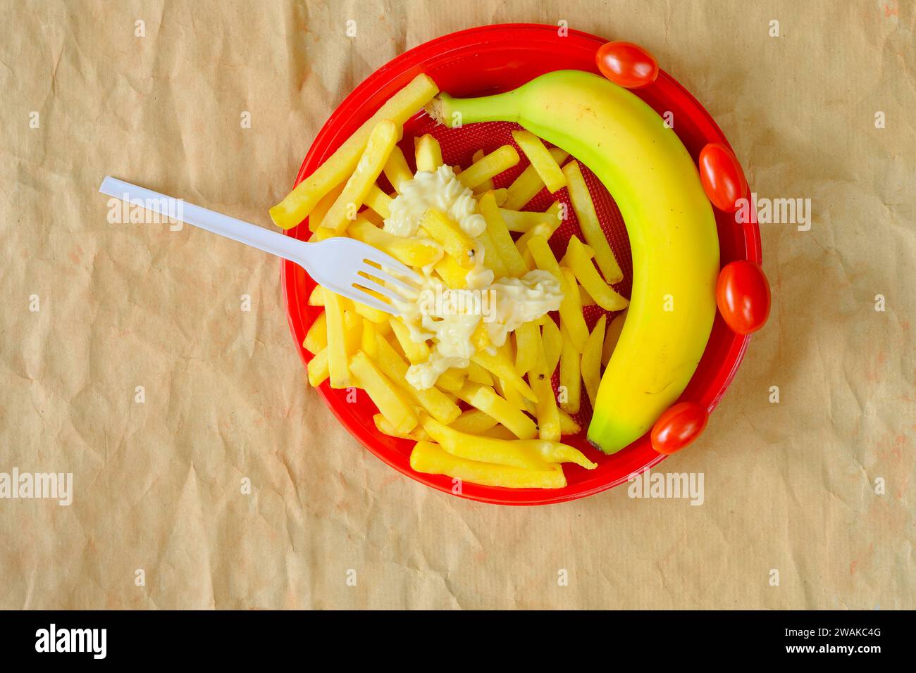 Concetto di dieta: Piatto di plastica con patatine fritte e una banana fresca e pomodori. Vestibilità e leggerezza per il concetto primaverile Foto Stock