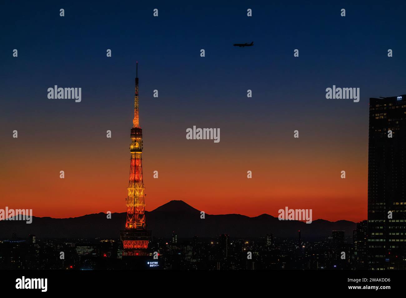 un aereo scende in un tramonto arancione mentre si avvicina alla torre di tokyo con la silhouette del monte fuji sullo sfondo Foto Stock