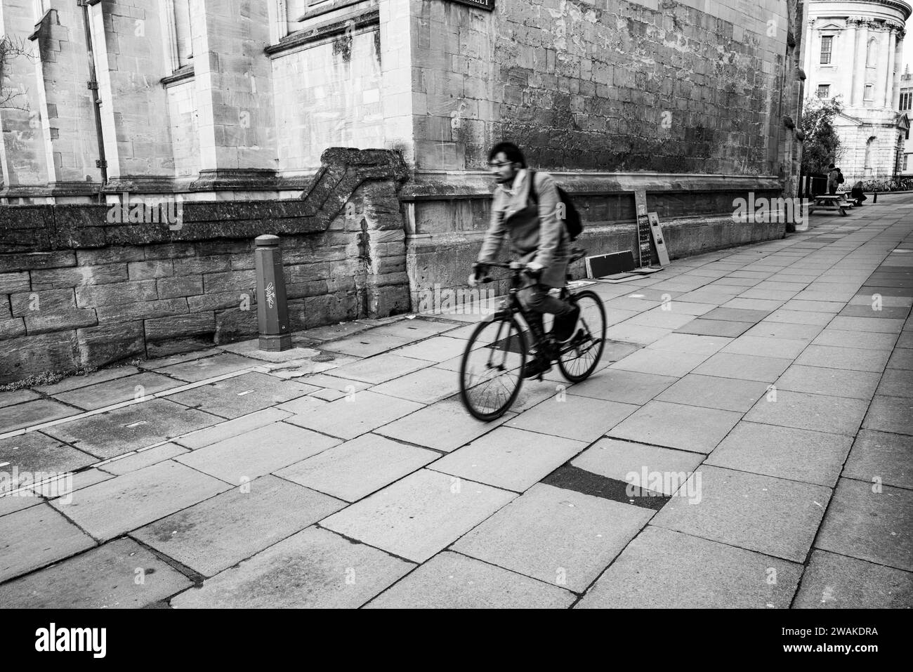 Ciclista che esce da Catte Street, Oxford, sulla strada principale Foto Stock