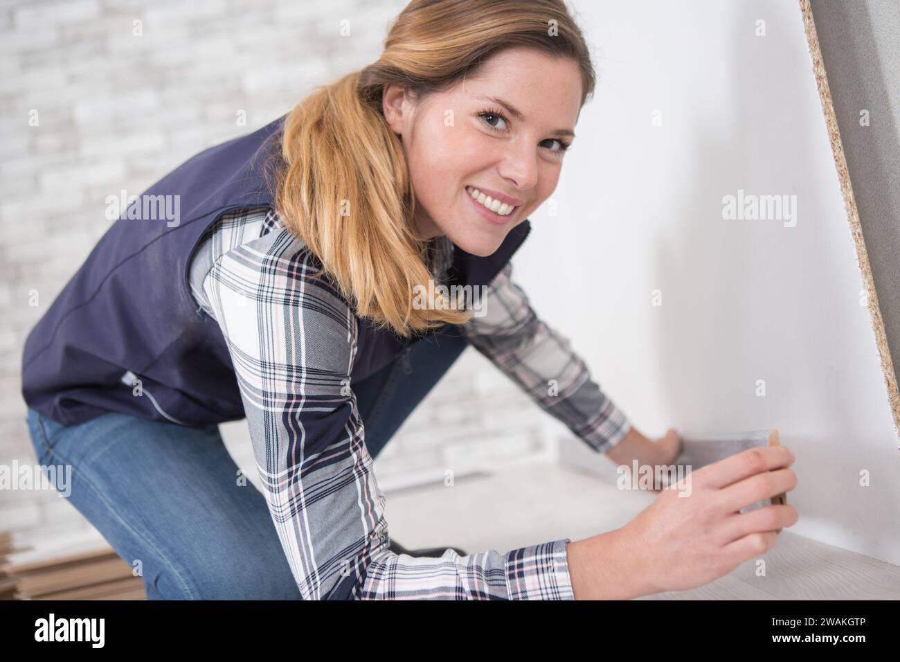 giovane donna felice che installa un nuovo pavimento Foto Stock