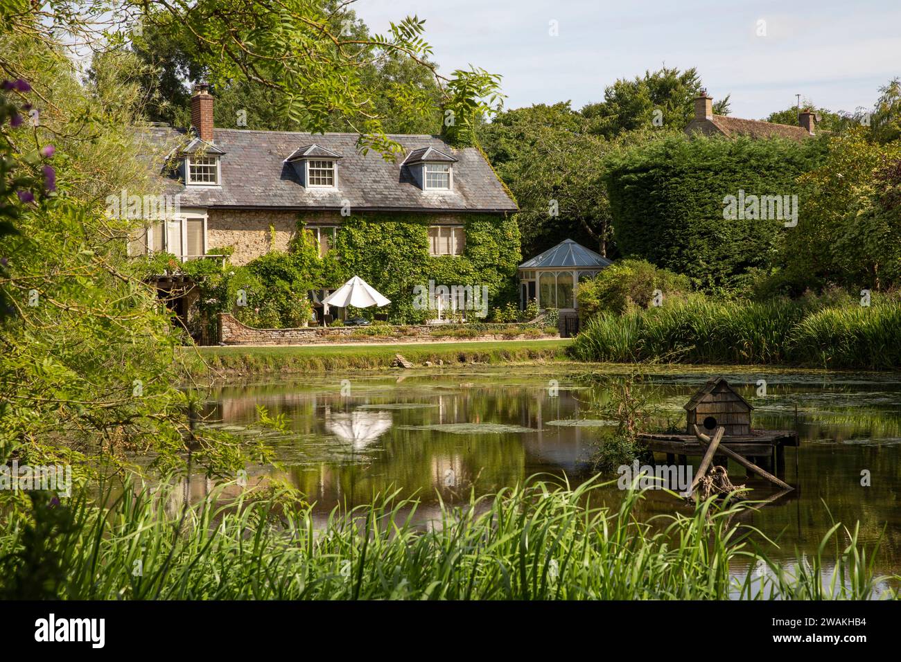 Regno Unito, Inghilterra, Oxfordshire, Fringford, casa ai margini dello stagno del villaggio Foto Stock