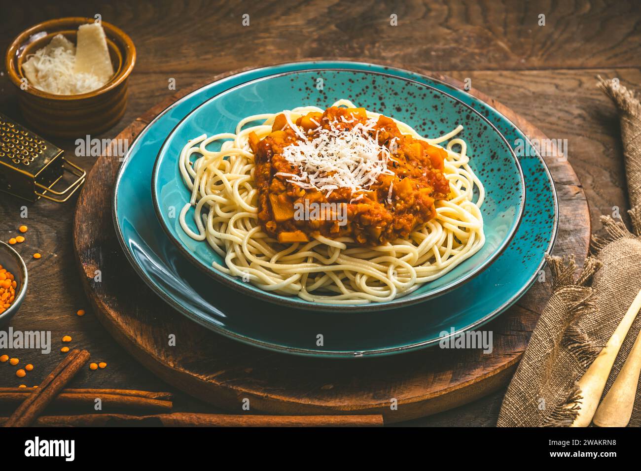 Spaghetti con salsa vegan alla bolognese fatta in casa a base di lenticchie rosse e zucca su fondo di legno, terracotta turchese Foto Stock
