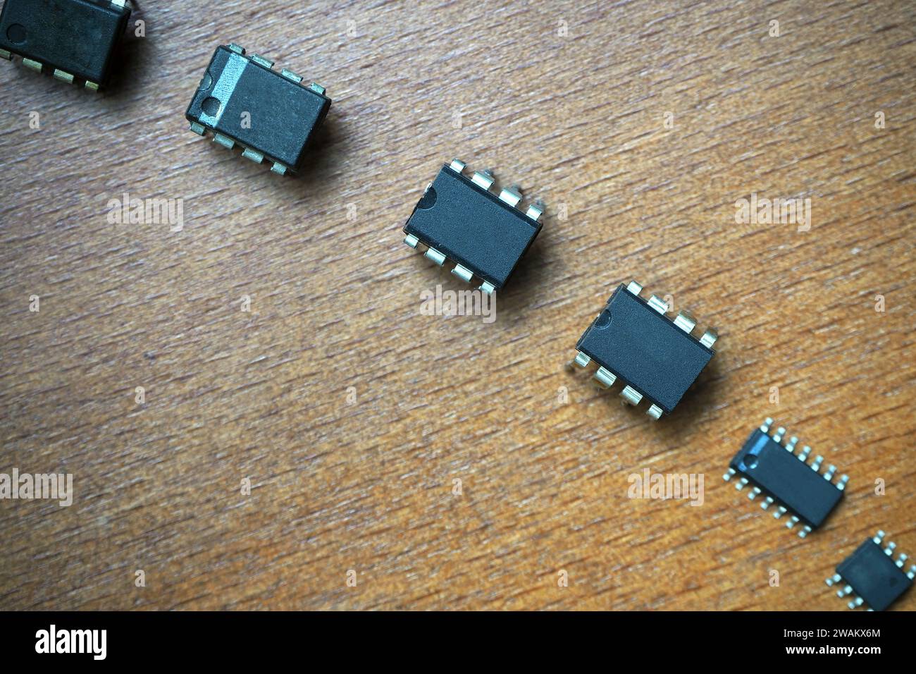 Circuiti integrati di fila. Componenti semiconduttori su pavimento in legno. Foto Stock