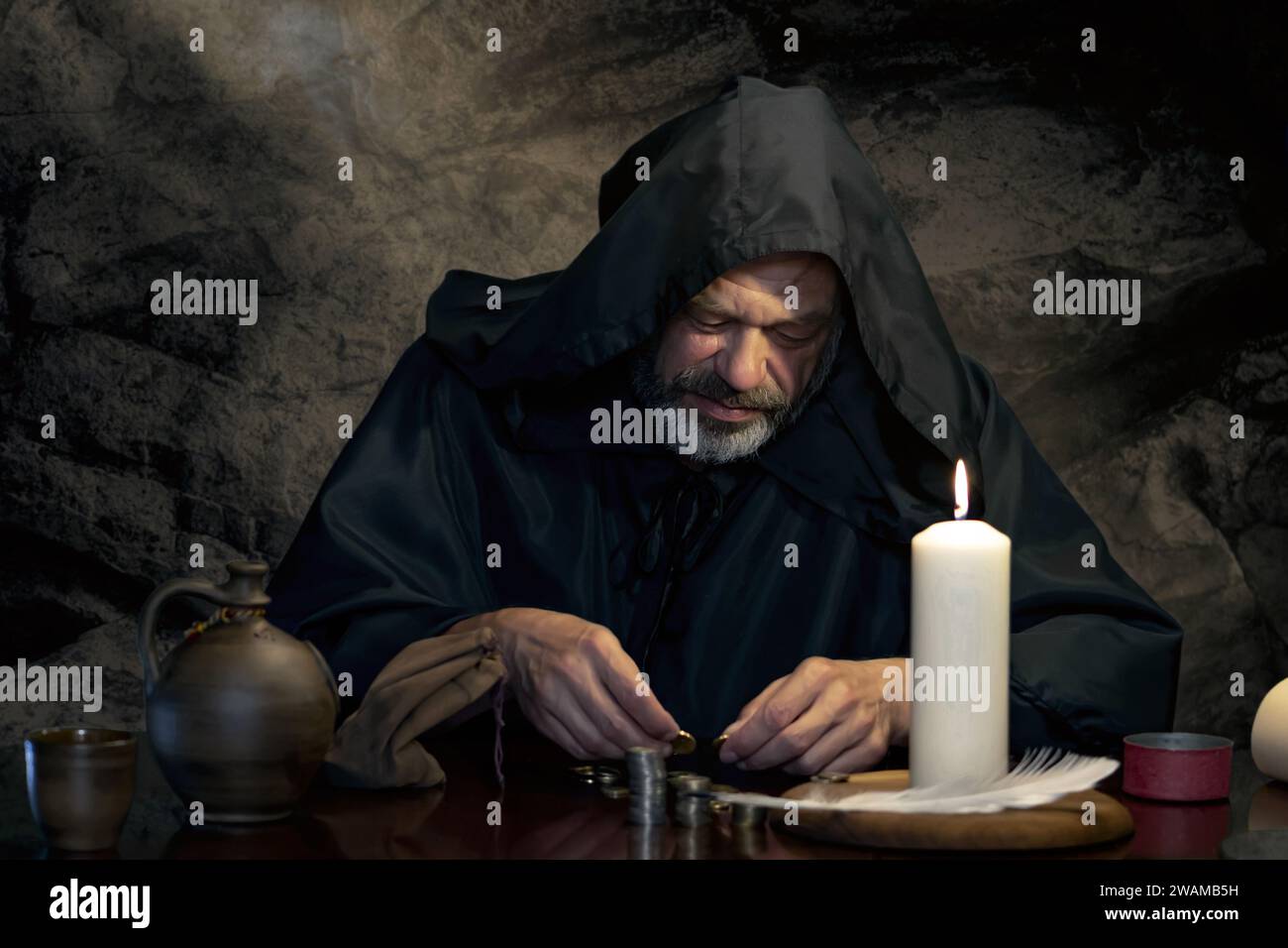Ritratto di un monaco in una cassoca, contando i soldi a lume di candela in una stanza di pietra scura, pile di monete. Nel Medioevo - esattore delle tasse, chiesa Treas Foto Stock