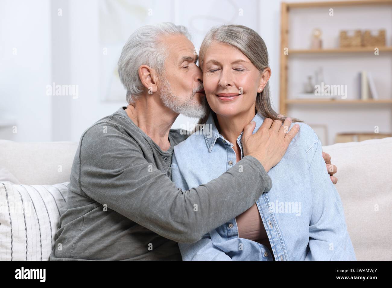 Uomo anziano che baciava la sua amata donna a casa Foto Stock