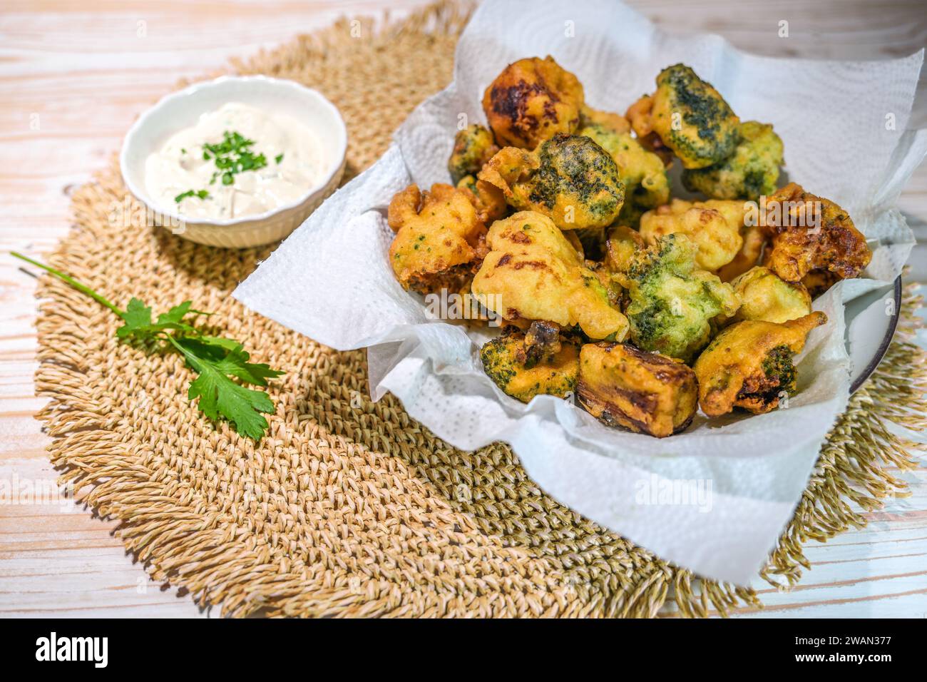 Verdure croccanti come broccoli e cavolfiore fritte in pastella di birra con un tuffo allo yogurt su una tovaglietta naturale e un tavolo in legno chiaro, copiare spp Foto Stock