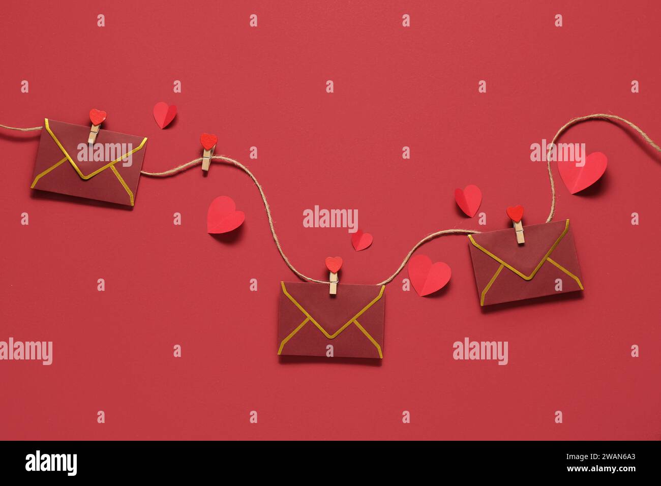 Composizione con buste appese su corda e cuori di carta su sfondo colorato. Festa di San Valentino Foto Stock