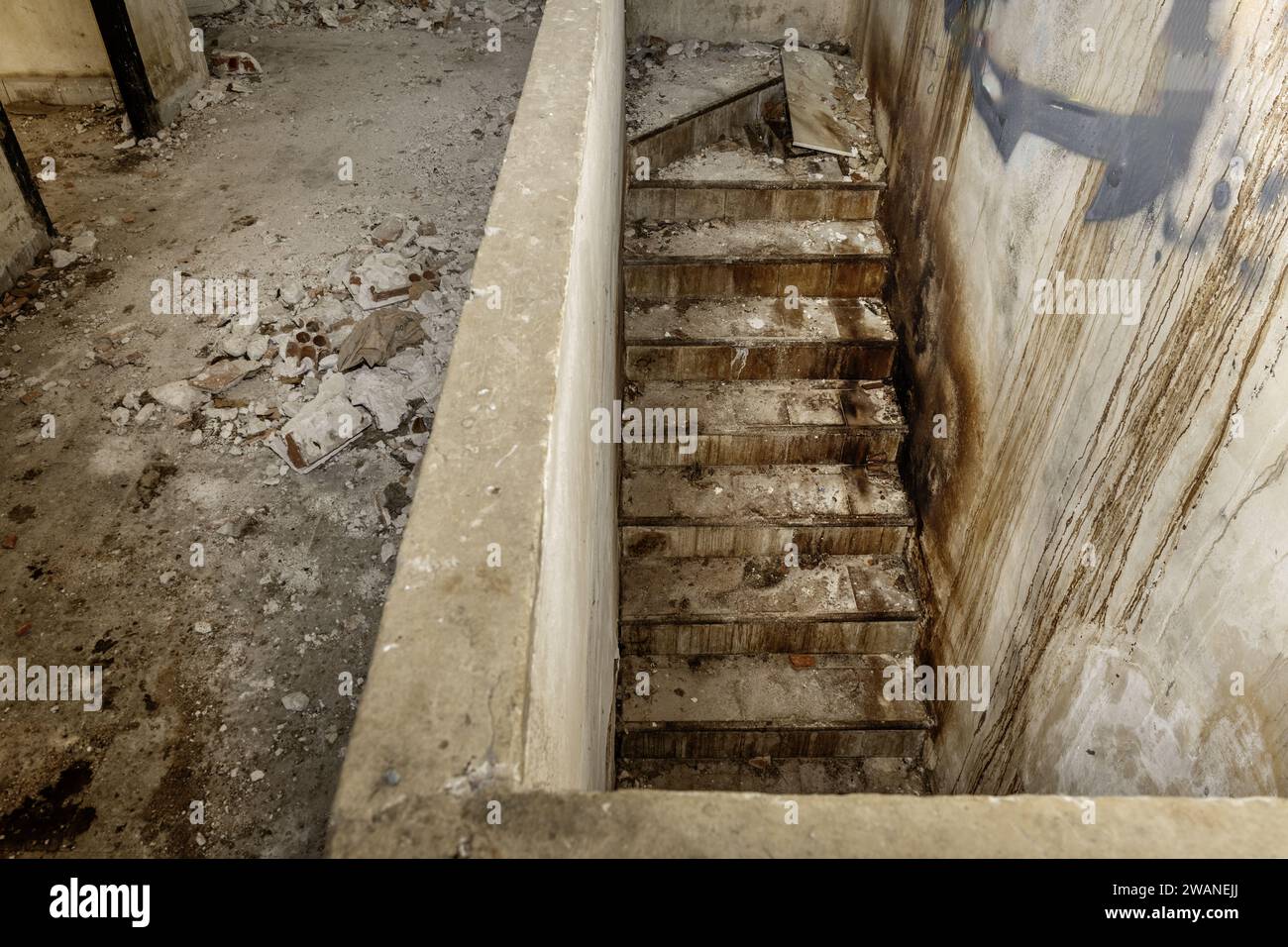 Al piano inferiore in un edificio in rovina pieno di sporcizia e detriti Foto Stock