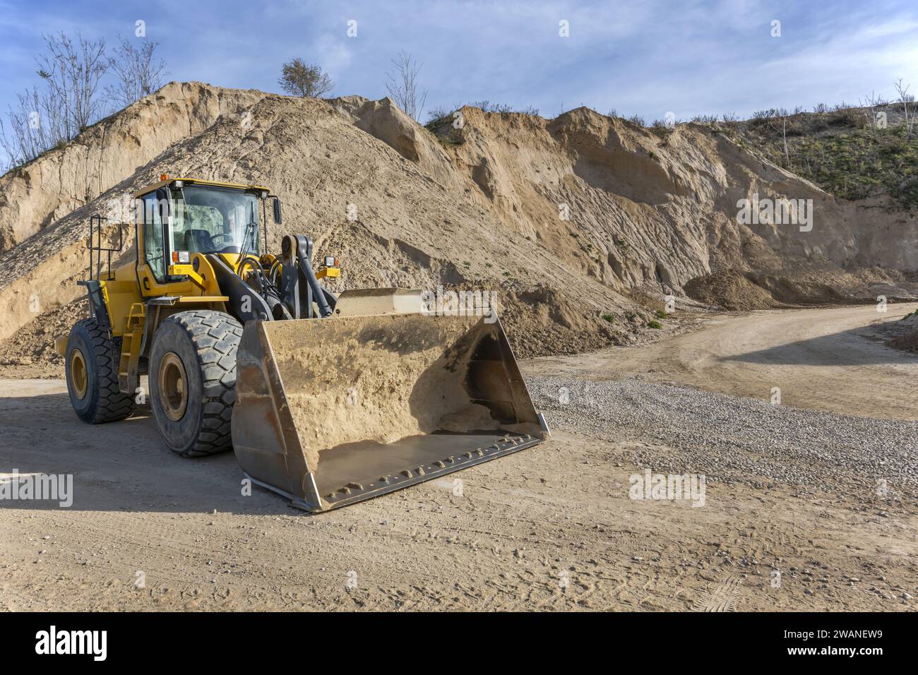 Macchine da costruzione autoportanti in piedi accanto a grandi cumuli di sabbia fluviale Foto Stock