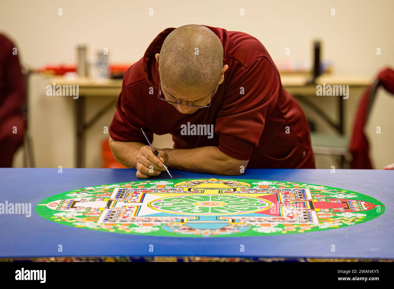 Un monaco buddista tibetano lavora per creare un mandala durante un evento di tour tenuto libero al pubblico dagli amici del Tibet di Placerville Foto Stock