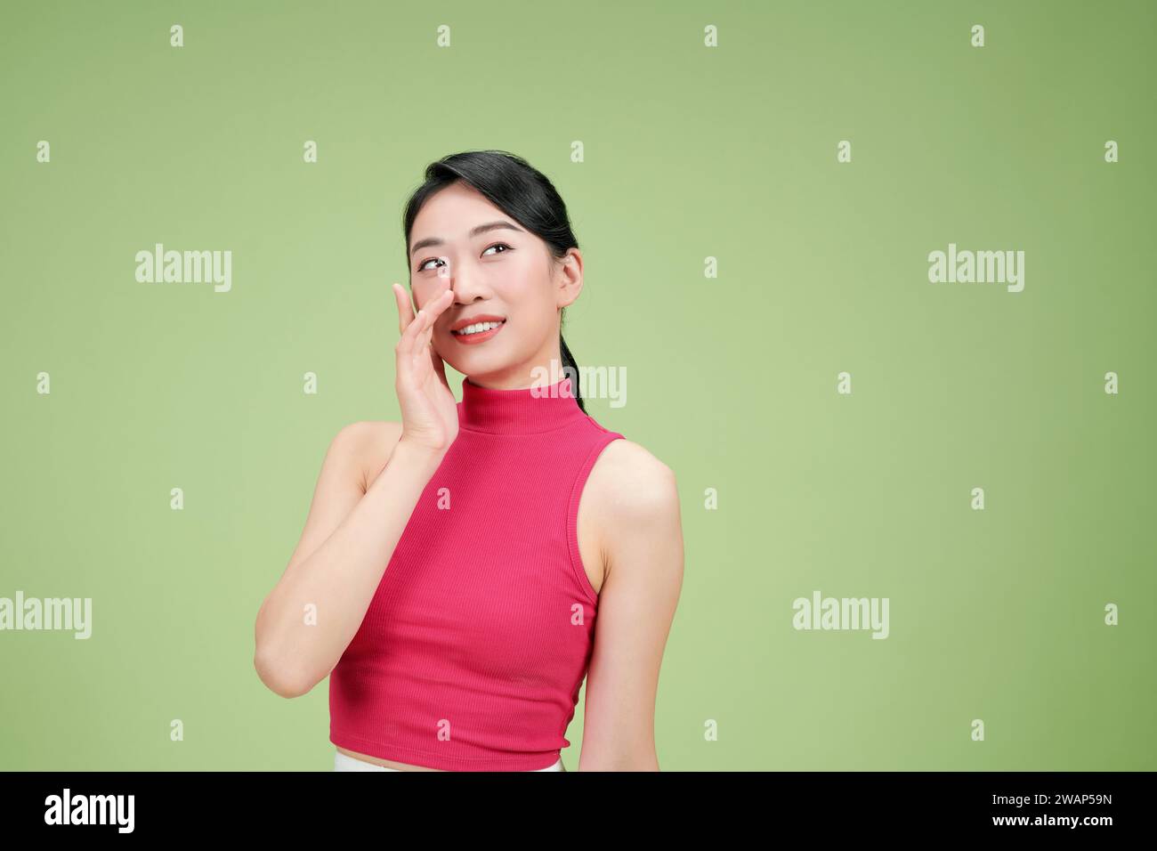 La bella donna asiatica solleva il tocco della mano sul labbro e sorride con felicità e timidezza Foto Stock
