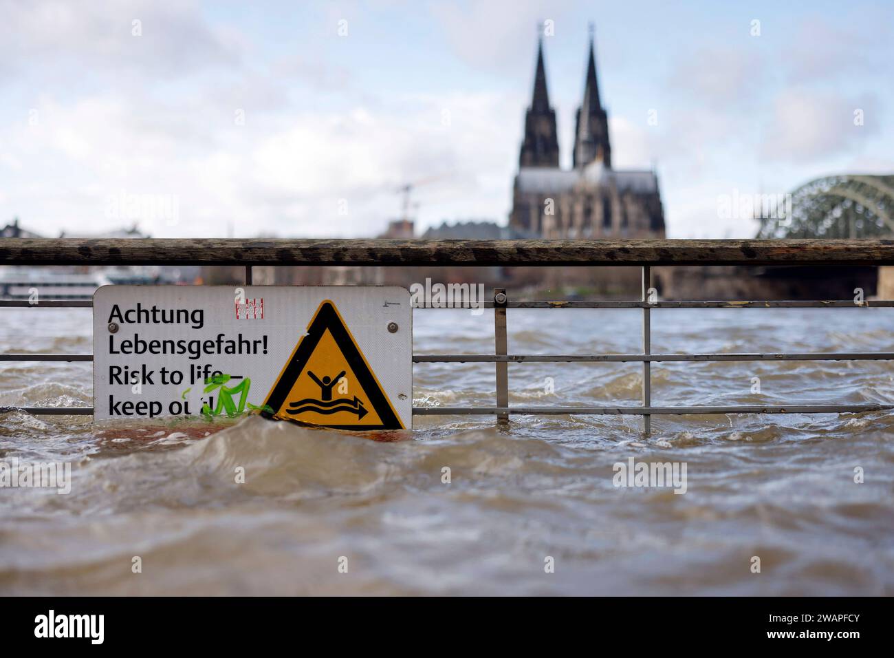 Impression vom Hochwasser in Köln am Ufer von Köln-Deutz: Am Ufer des Rhein sind Teile des Rheinboulevard, Gehwege und Wiesen überflutet. Absperrungen weisen auf Lebensgefahr bei Hochwasser Hin. DAS nasse Wetter Hat die Pegel von Bächen und Flüssen steigen lassen. Böden sind aufgeweicht und können kein weiteres Wasser fassen. für die kommenden Tage wird Dauerregen befürchtet. Themenbild, Symbolbild Köln, 03.01.2024 NRW Deutschland *** impressione delle inondazioni a Colonia sulle rive di Colonia Deutz sulle rive del Reno, parti del RheinBoulevard, sentieri e prati sono allagati Bar Foto Stock