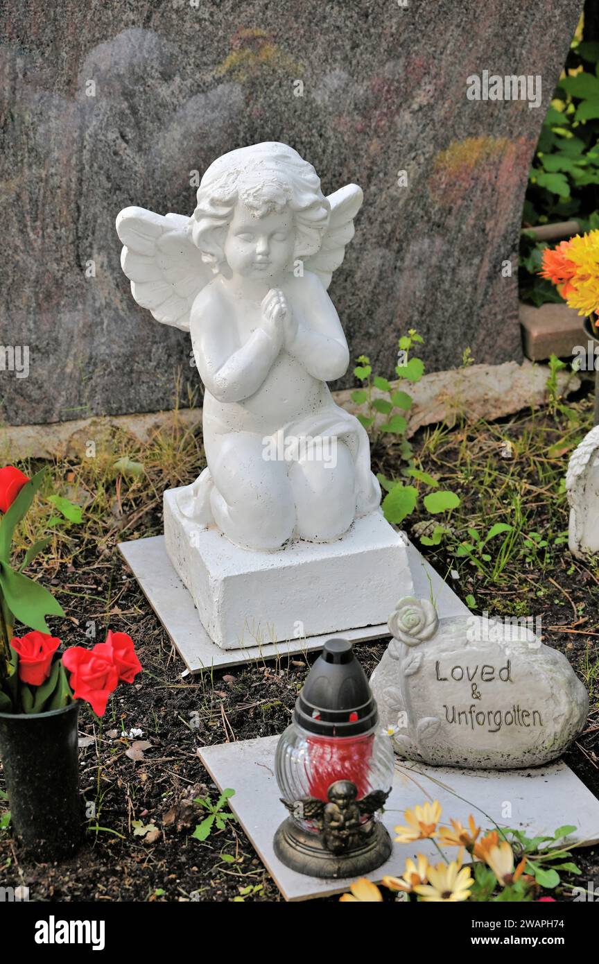 Decorazione di tombe con piccolo angelo di preghiera e pietra con l'iscrizione "amato e indimenticabile" Foto Stock