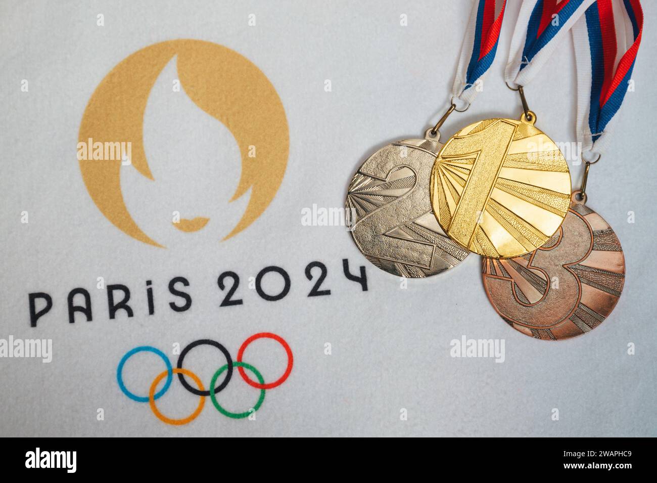 PARIGI, FRANCIA, DICEMBRE. 4. 2023: Logo della partita olimpica estiva a Parigi 2024 e set di medaglie vincenti. Medaglia d'oro, argento e bronzo. Sfondo bianco. Foto Stock
