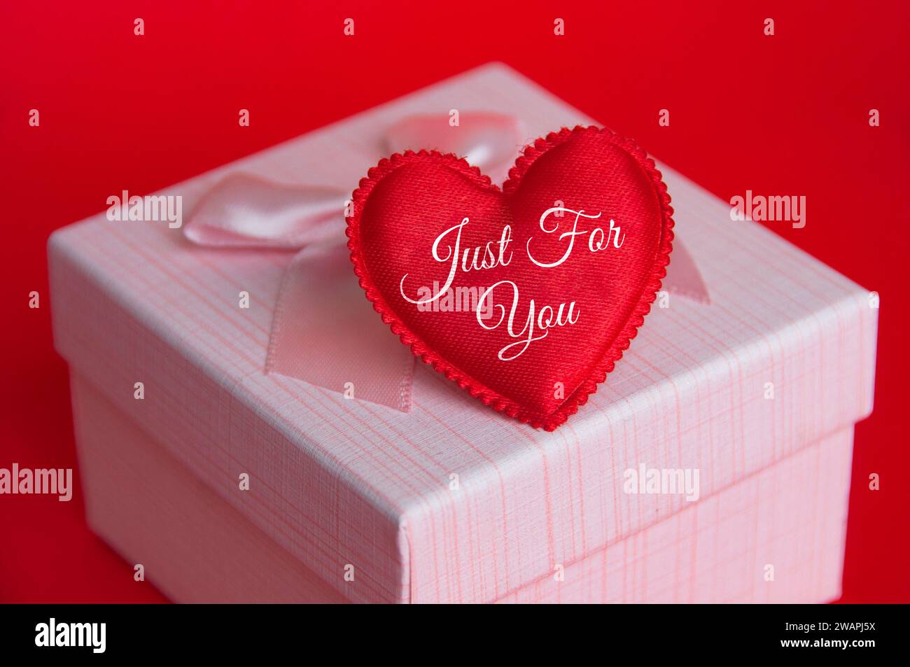 Solo per te testo sulla forma del cuore in cima al presente su sfondo rosso. Foto Stock