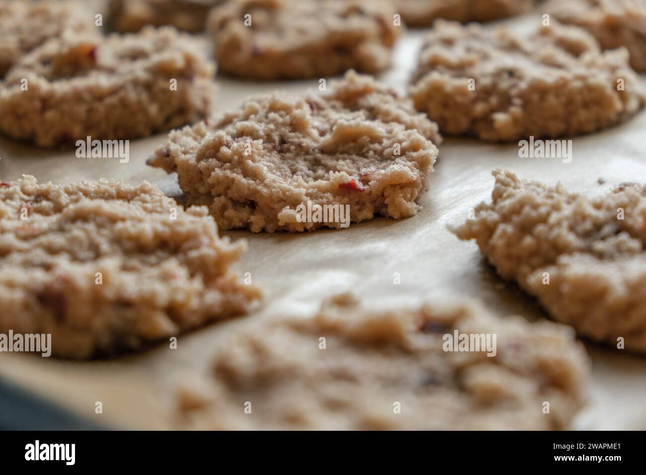 primo piano dei biscotti keto di farina di mandorle appena sfornati rivestiti su carta pergamena pronti da portare in forno Foto Stock