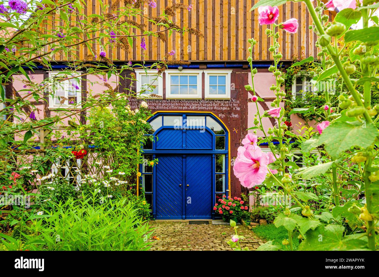 Blühender Bauerngarten vor historischem Fachwerkhaus mit traditioneller Hausinschrift in Nordhessen, Deutschland, Europa Foto Stock