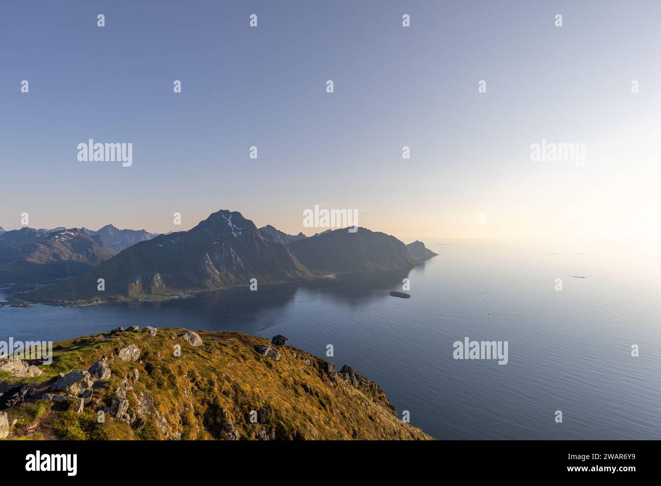 La luce soffusa del sole di mezzanotte bagna l'aspro paesaggio di Offersoykammen, affacciato sul tranquillo stretto di Nappstraumen nell'arcipelago delle Lofoten Foto Stock