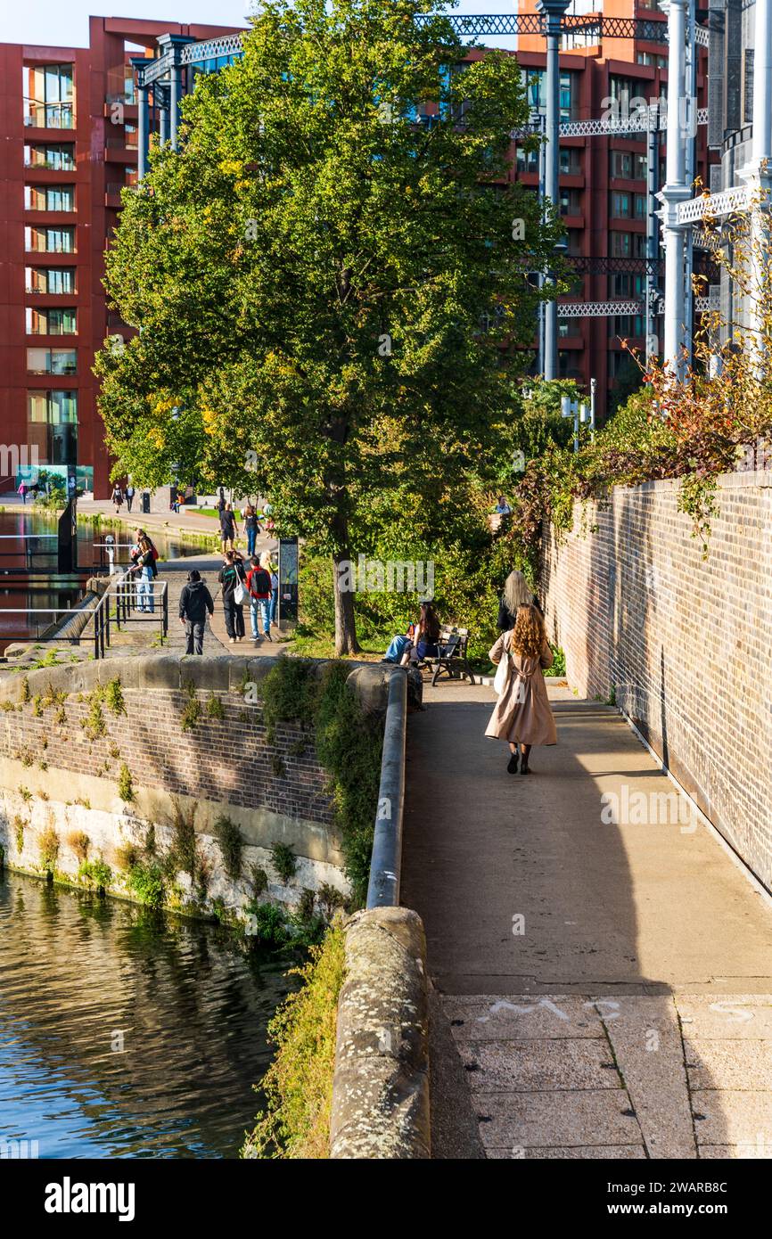 Gente che cammina lungo Regent's Canal Towpath vicino al Somers Town Bridge, con Battlebridge Basin sullo sfondo, Londra, Regno Unito Foto Stock