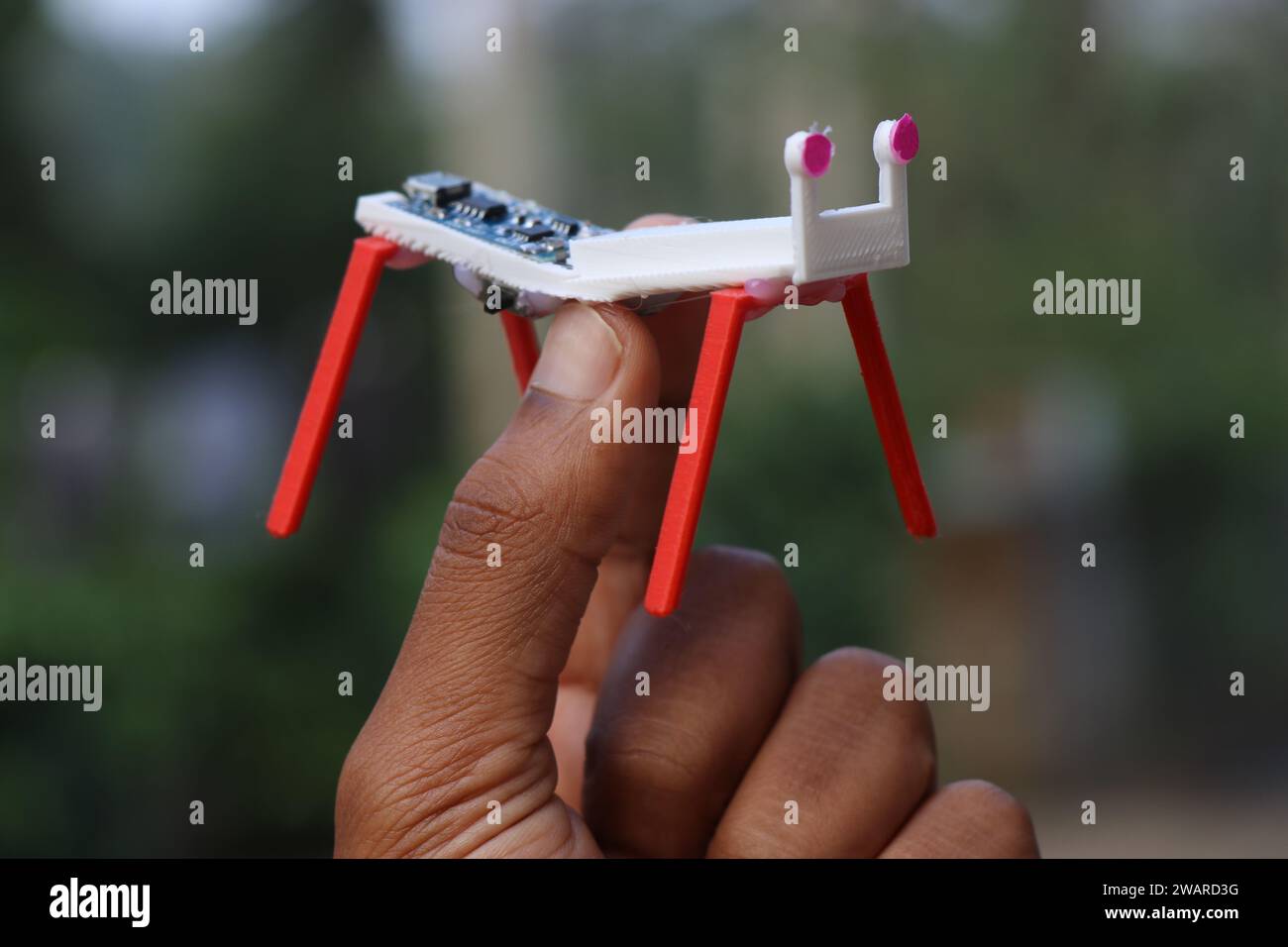 Modello di un piccolo robot a quattro gambe realizzato utilizzando la tecnologia di stampa 3D e semplici componenti elettronici tenuti in mano Foto Stock