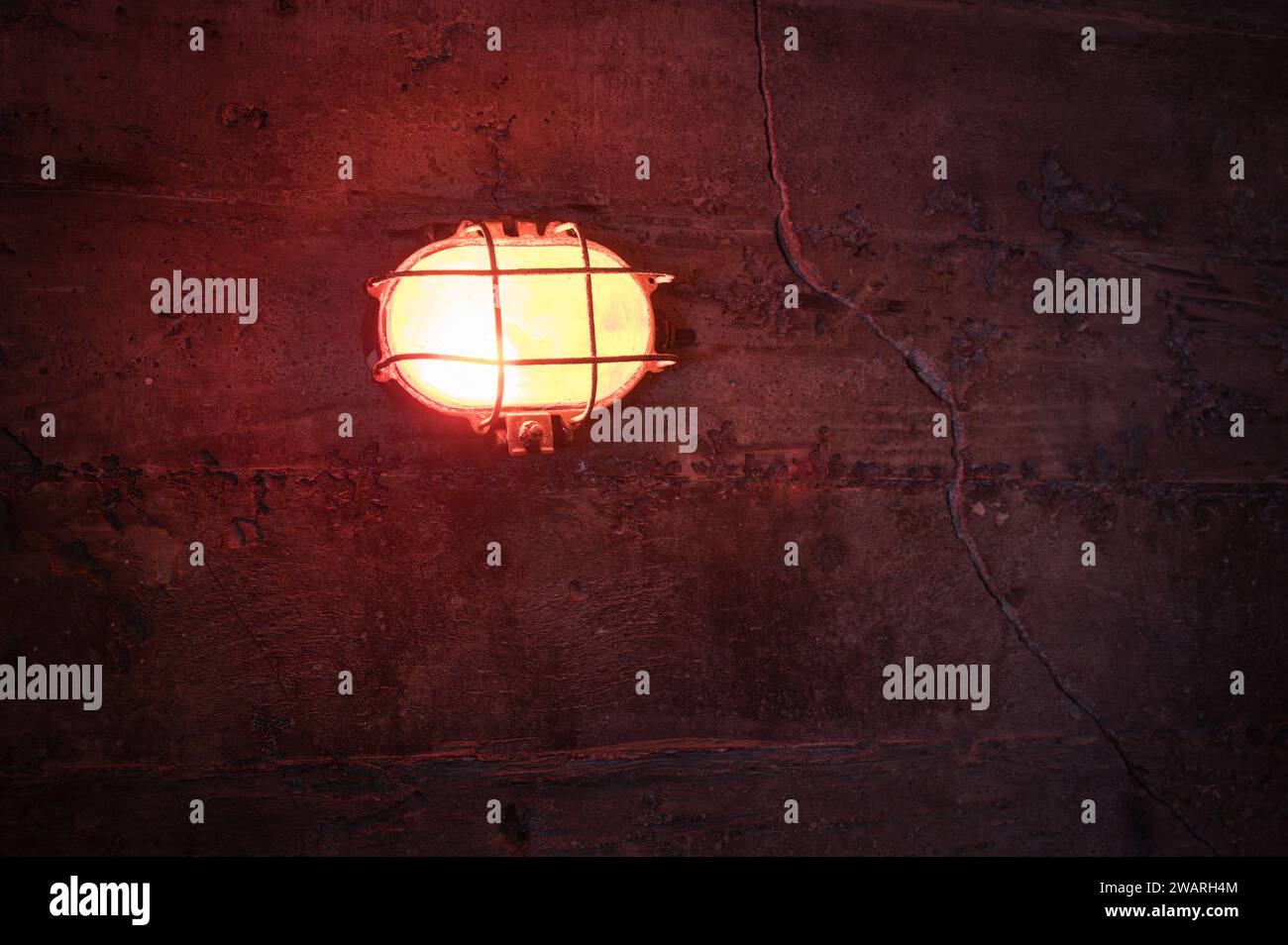 Dettaglio di una lampada da parete rossa in un vecchio bunker freddo e scuro della seconda guerra mondiale Foto Stock