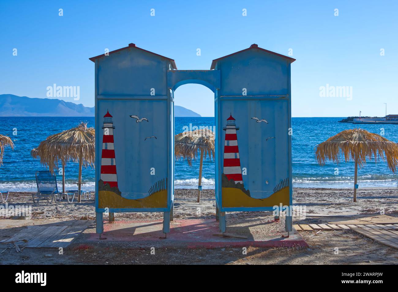 Armadio decorato, lettini e ombrelloni sulla spiaggia di un'isola greca Foto Stock