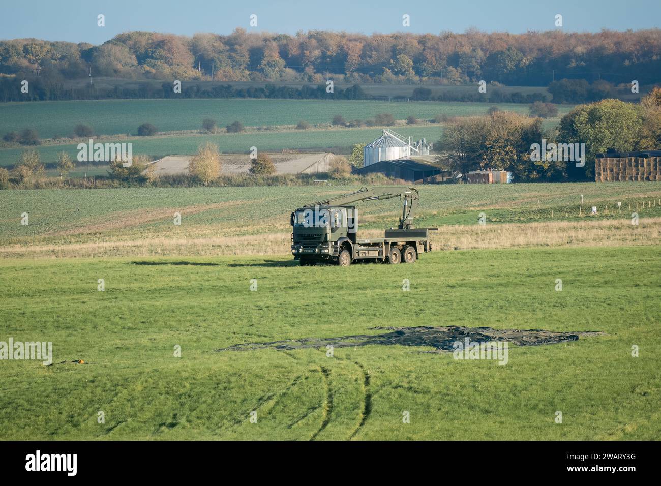 Camion logistico A pianale SX 6x6 dell'esercito britannico con gru in un campo di erba verde, che recupera pallet CDS da una caduta di paracadute. Wilts UK Foto Stock