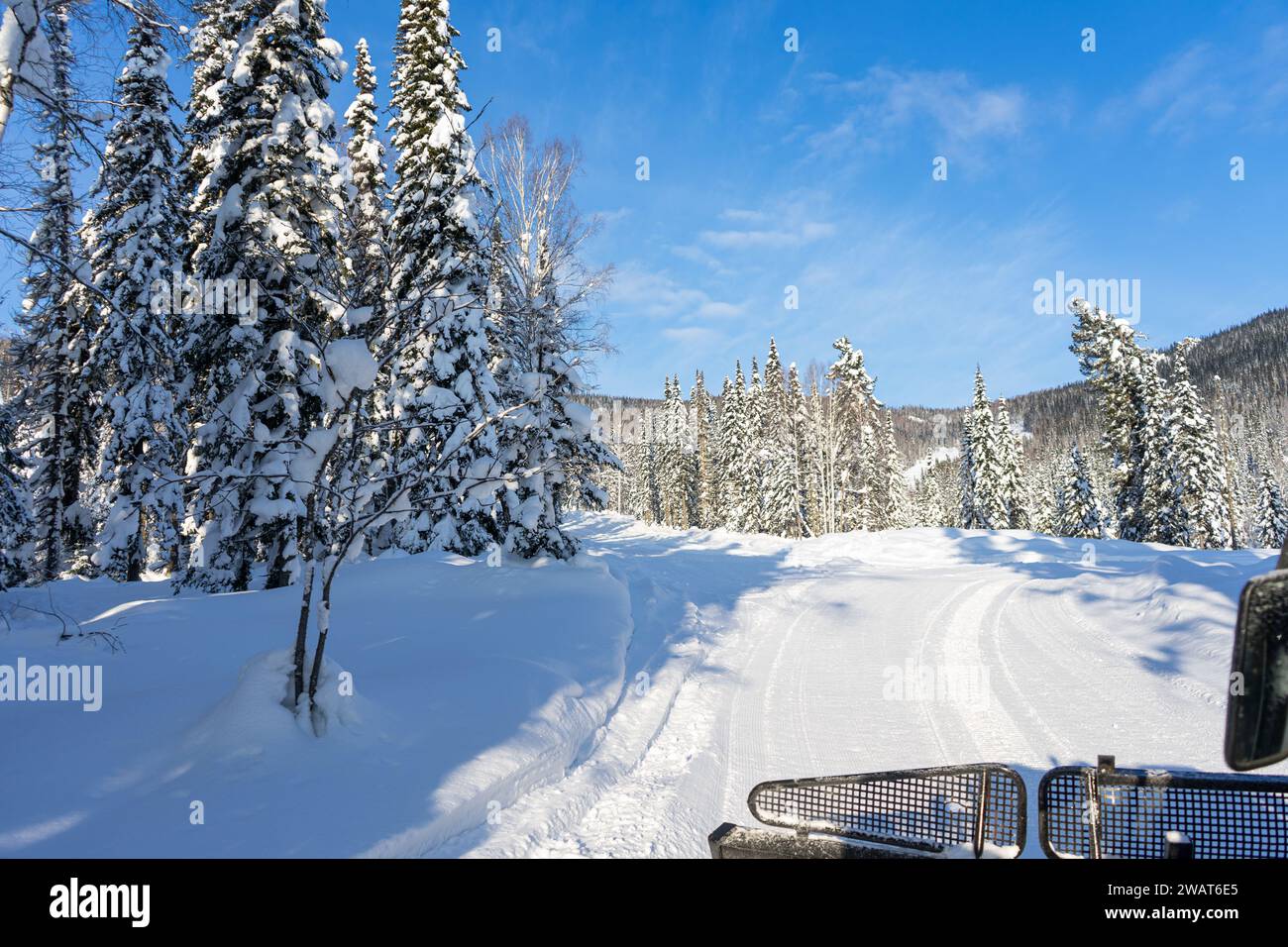 Strada invernale. Escursioni in gatto delle nevi rosse in una foresta di abeti rossi innevati, vista dalla cabina. Gita in Freeride per sciatori e snowboarder. Foto Stock