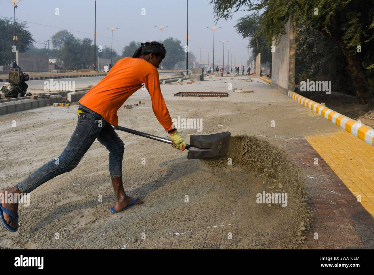 Ayodhya, India. 27 dicembre 2023. Un operaio poggia sabbia sulle pietre di pavimentazione di una pavimentazione di nuova costruzione prima della visita del primo ministro indiano Narendra modi in un cantiere di Ayodhya. Ramnagari Ayodhya, un tempo nota per le sue strade strette e le strade in decomposizione, sta facendo progressi costanti: Tutte le strade e gli edifici che portano a RAM Janmabhoomi sono stati ampliati e ristrutturati per facilitare i viaggi. (Foto di Biplov Bhuyan/SOPA Images/Sipa USA) credito: SIPA USA/Alamy Live News Foto Stock