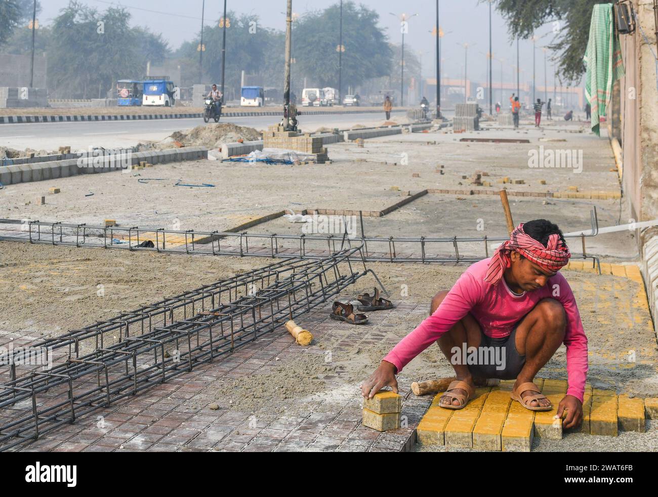 Ayodhya, India. 27 dicembre 2023. Un lavoratore installa pietre di pavimentazione prima della visita del primo ministro indiano Narendra modi nei pressi di un cantiere di Ayodhya. Ramnagari Ayodhya, un tempo nota per le sue strade strette e le strade in decomposizione, sta facendo progressi costanti: Tutte le strade e gli edifici che portano a RAM Janmabhoomi sono stati ampliati e ristrutturati per facilitare i viaggi. (Foto di Biplov Bhuyan/SOPA Images/Sipa USA) credito: SIPA USA/Alamy Live News Foto Stock