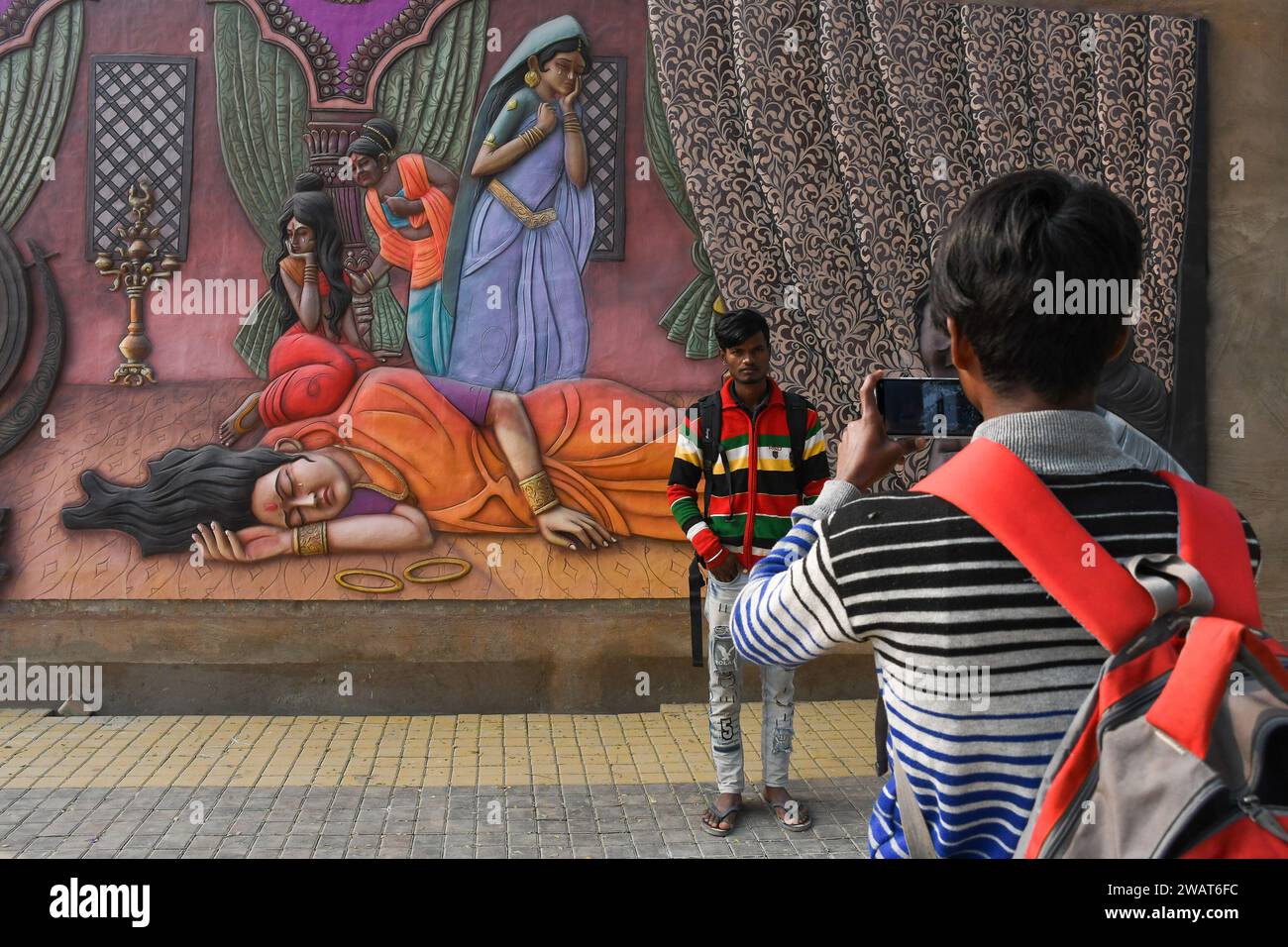 Ayodhya, India. 27 dicembre 2023. Le persone scattano foto di fronte a una scultura d'arte che raffigura la storia del Ramayana prima della visita del primo ministro indiano Narendra modi ad Ayodhya. Ramnagari Ayodhya, un tempo nota per le sue strade strette e le strade in decomposizione, sta facendo progressi costanti: Tutte le strade e gli edifici che portano a RAM Janmabhoomi sono stati ampliati e ristrutturati per facilitare i viaggi. (Foto di Biplov Bhuyan/SOPA Images/Sipa USA) credito: SIPA USA/Alamy Live News Foto Stock