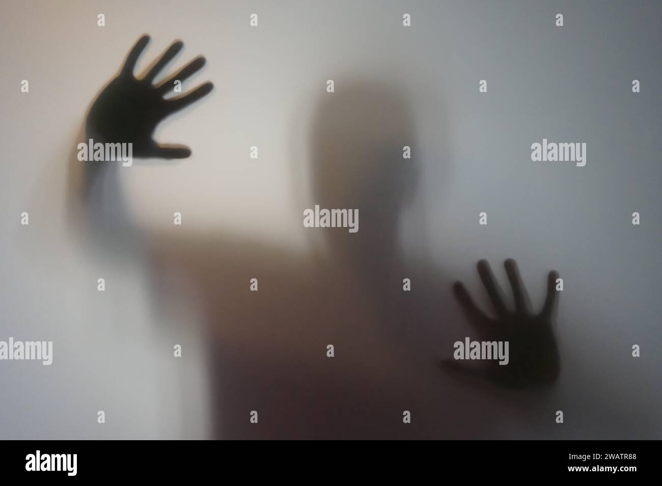 Uomo con le mani rialzate dietro vetro smerigliato Foto Stock