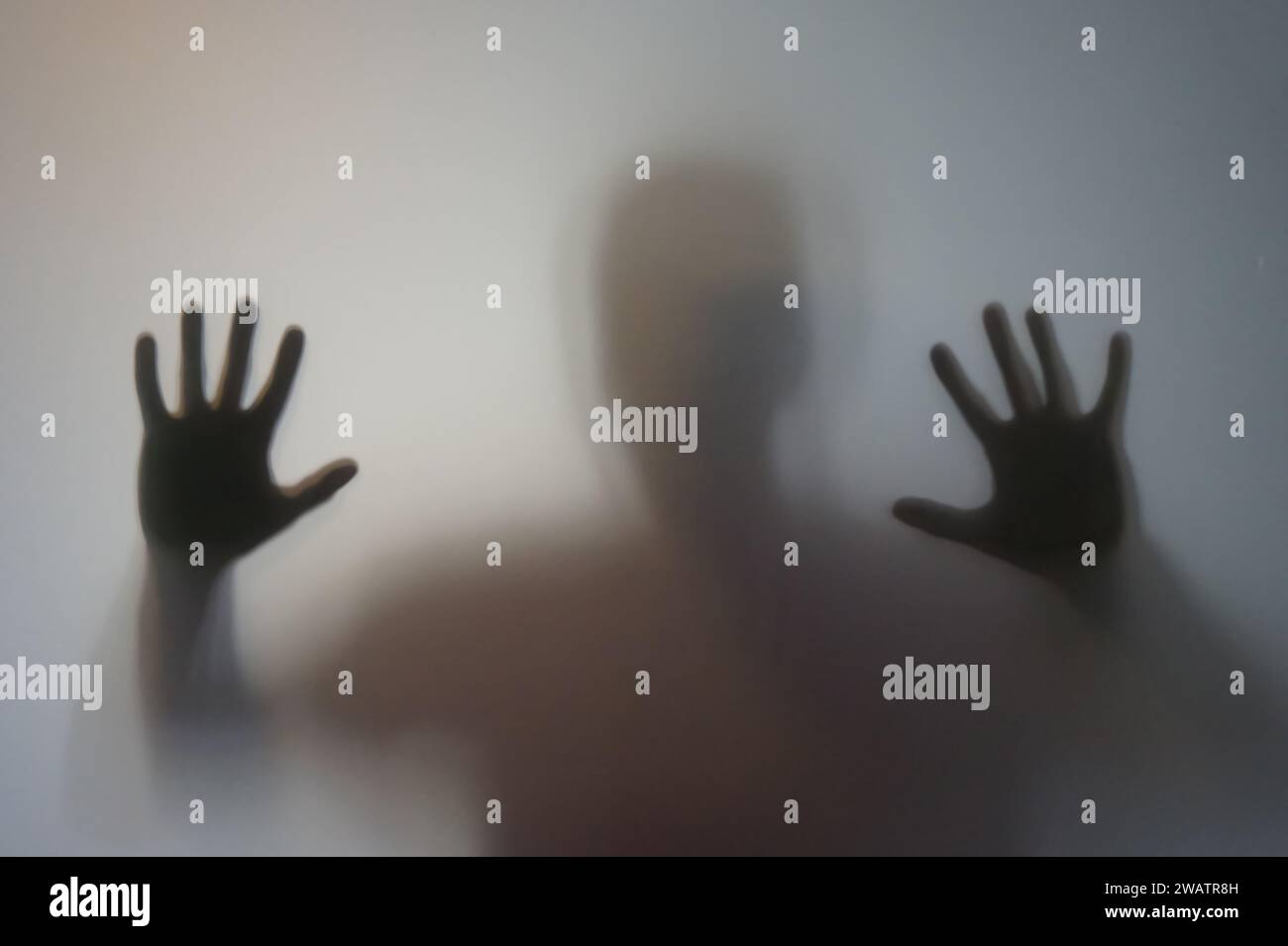 Uomo con le mani rialzate dietro vetro smerigliato Foto Stock