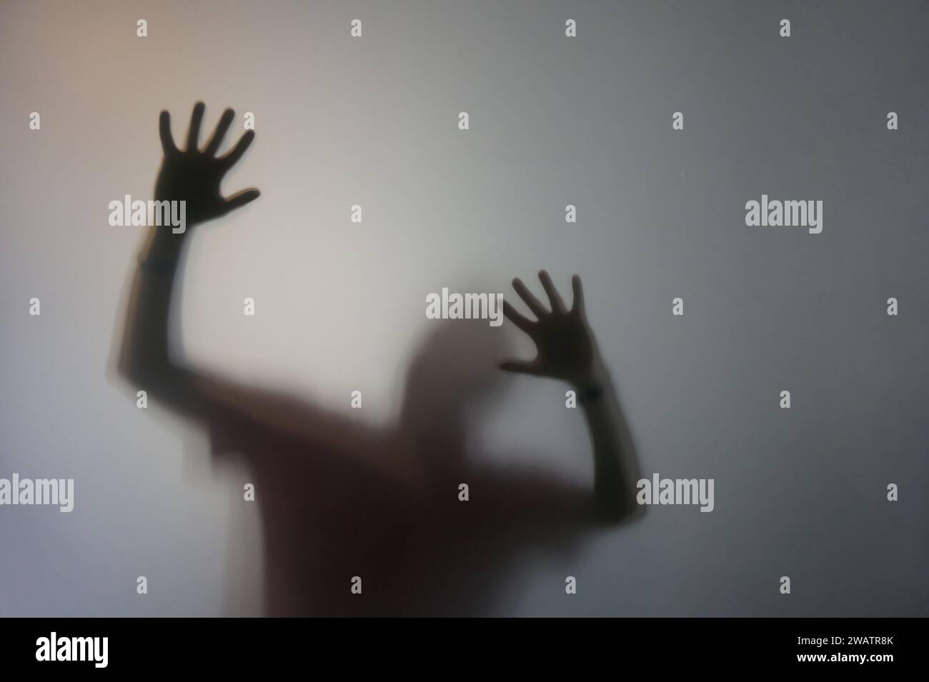 Uomo con le mani rialzate dietro vetro smerigliato Foto Stock