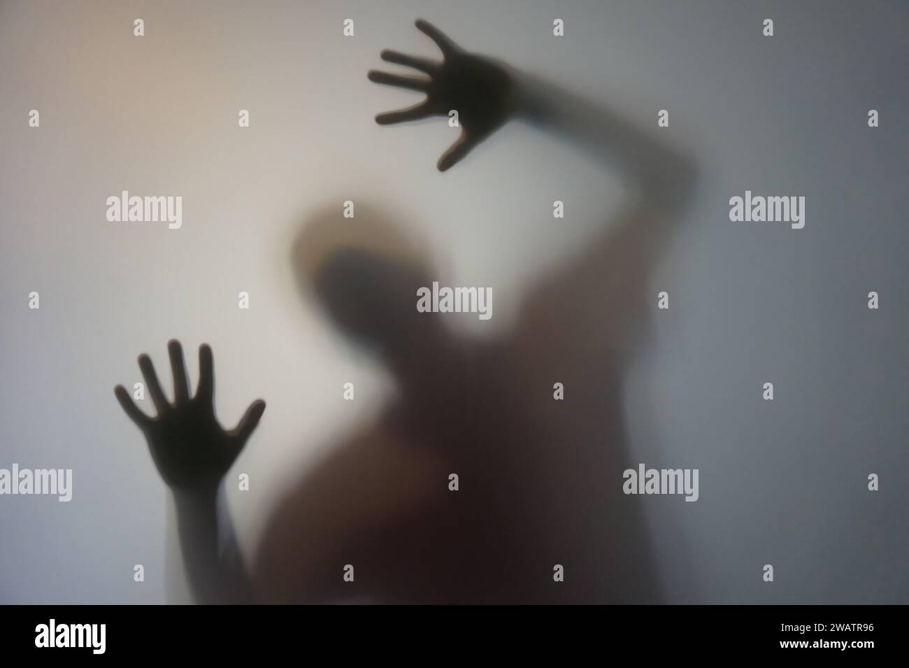 Uomo con le mani rialzate dietro vetro smerigliato Foto Stock