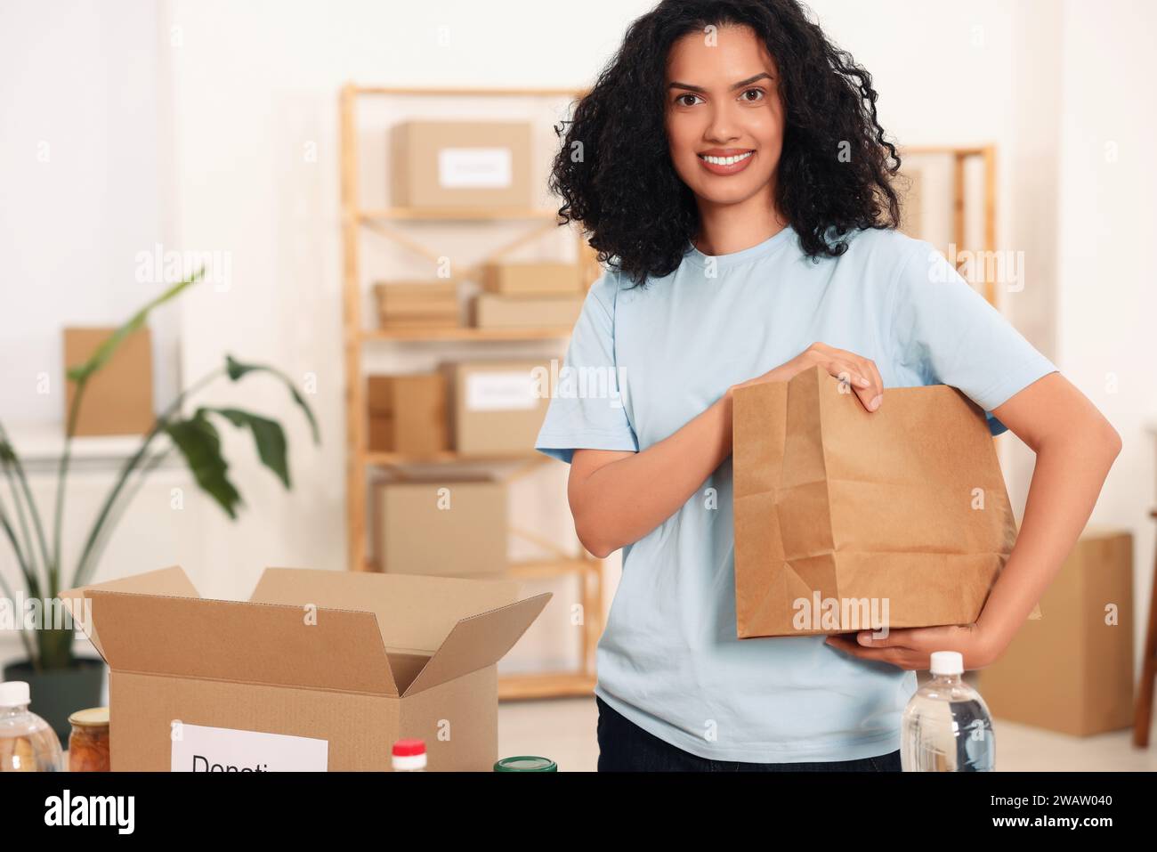 Volontariato. Donna felice con un sacco di carta in magazzino Foto Stock