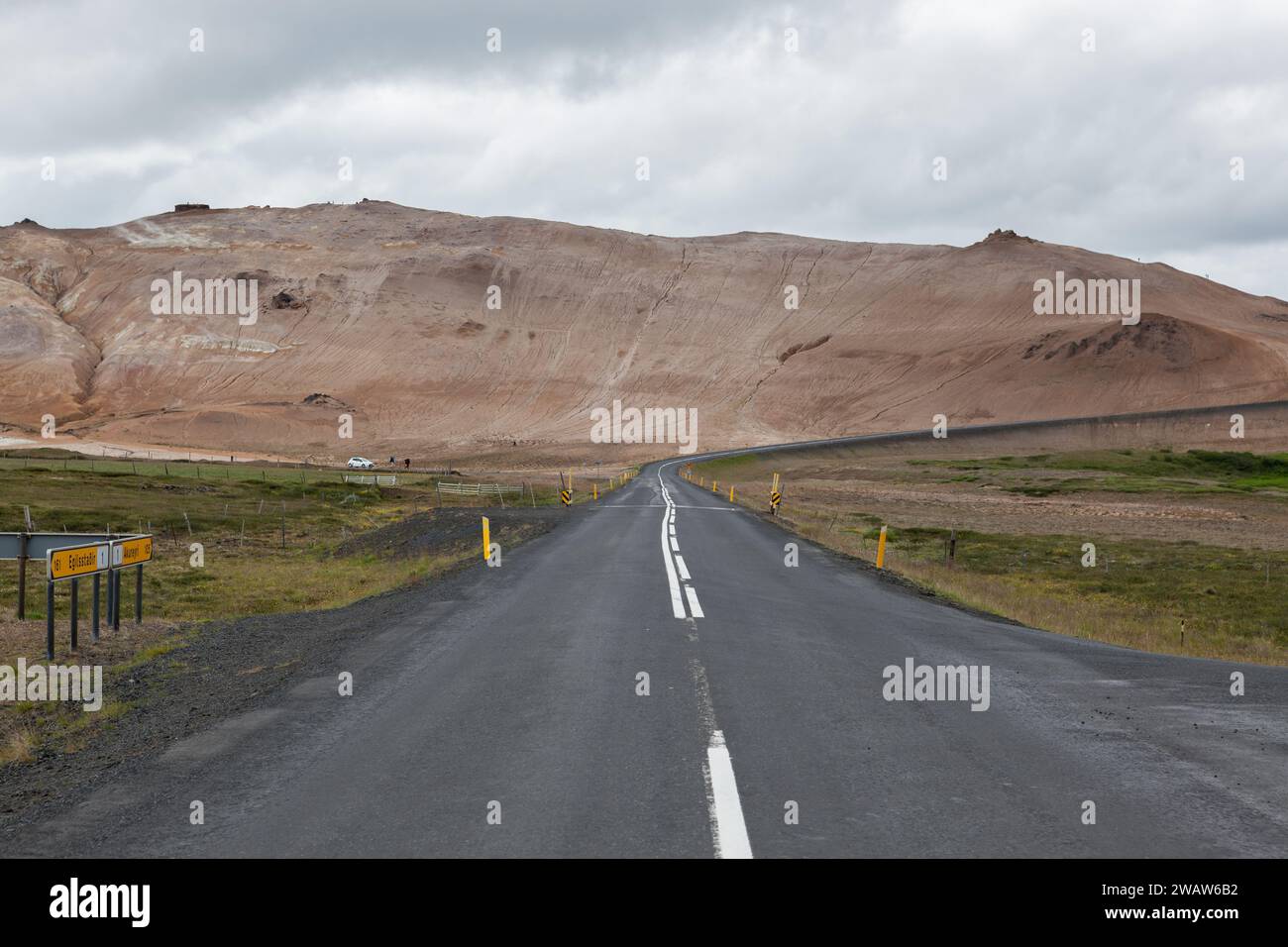 Islanda Road con montagne marroni all'orizzonte. Strada vuota nel paesaggio rurale islandese. Nuvoloso giorno d'estate. Foto Stock