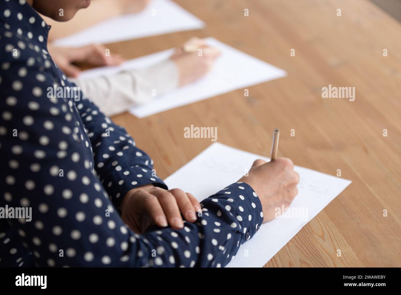 Diversi studenti siedono alla scrivania per scrivere insieme un esame Foto Stock