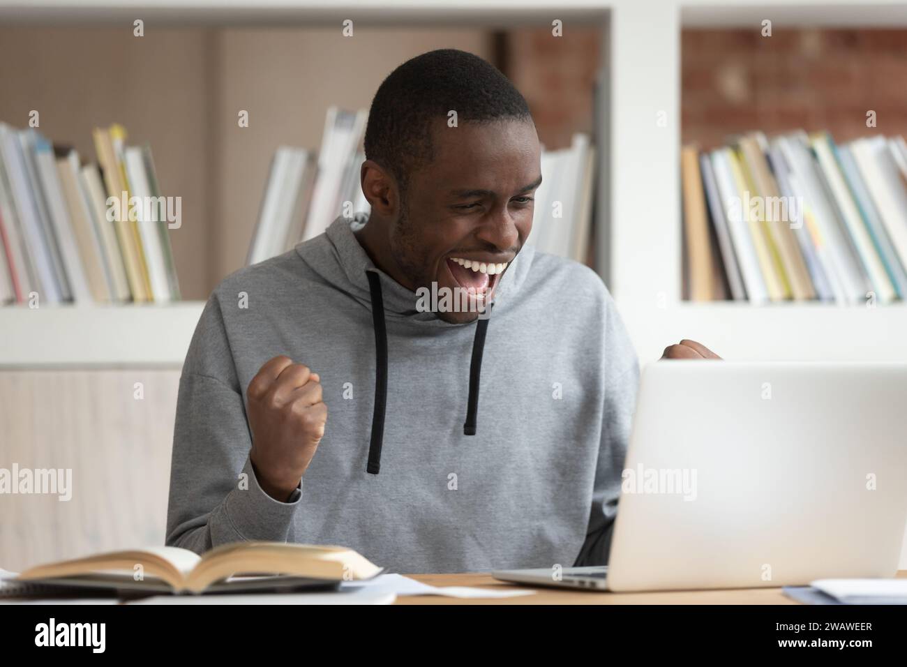 Felicissimo ragazzo afro-americano riceve e-mail positive sul portatile Foto Stock