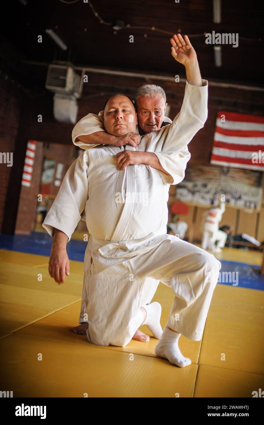 L'istruttore di Judo sensei in gi kimono tradizionale dimostra la tecnica del judo sul tatami Foto Stock