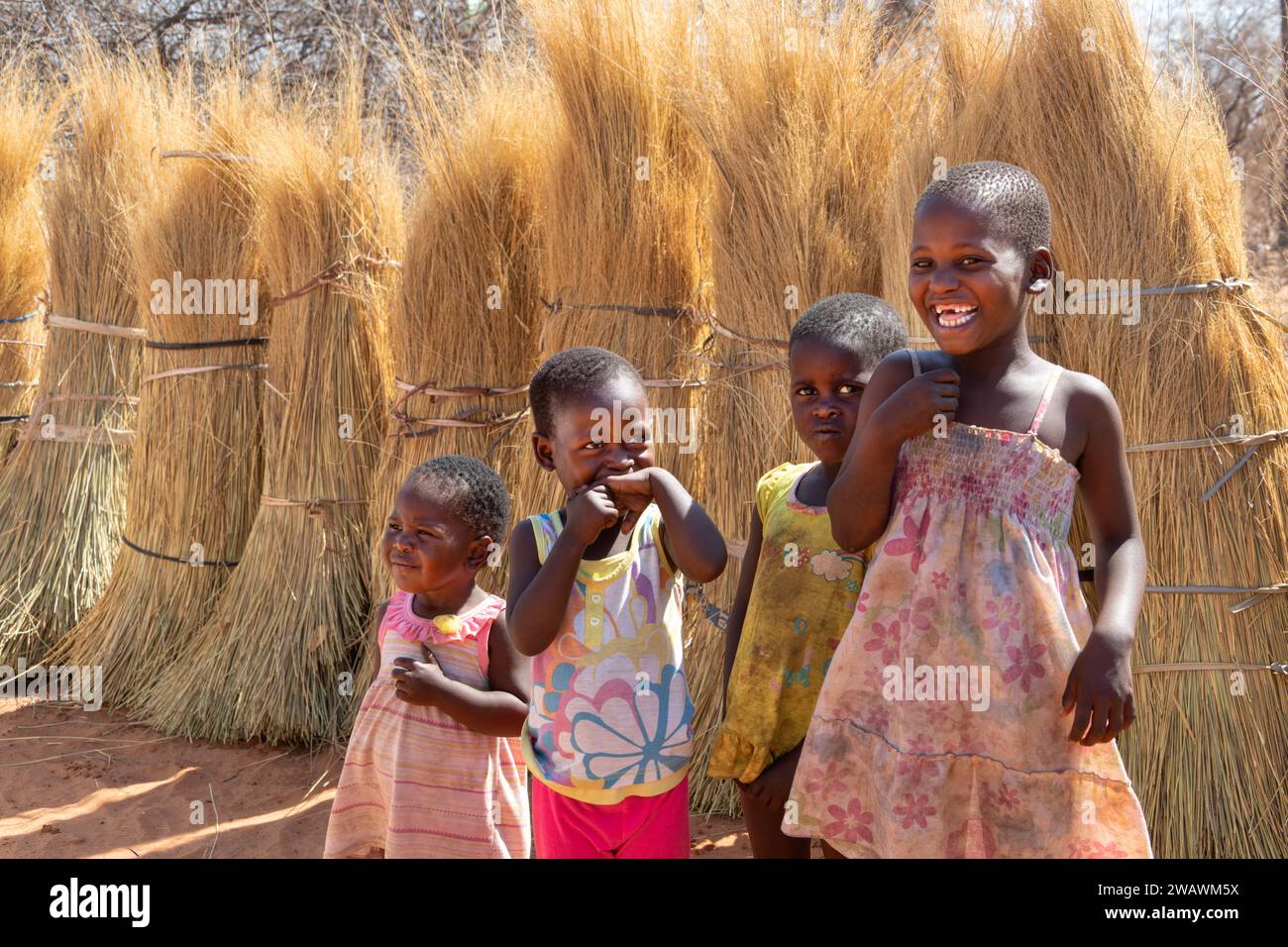 Famiglia di bambini africani che giocano insieme davanti all'erba di paglia, vita di un villaggio Foto Stock