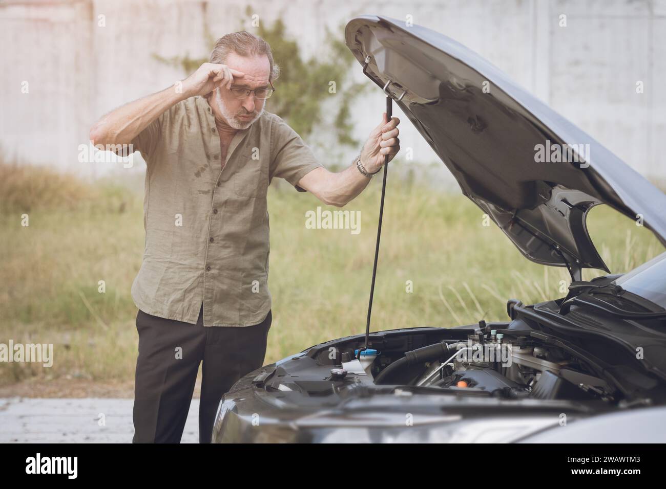 Anziano anziano auto maschile rotto hanno un guasto motore da solo nessuno aiuta ad aprire il cofano per autocontrollo sul lato della strada. Foto Stock