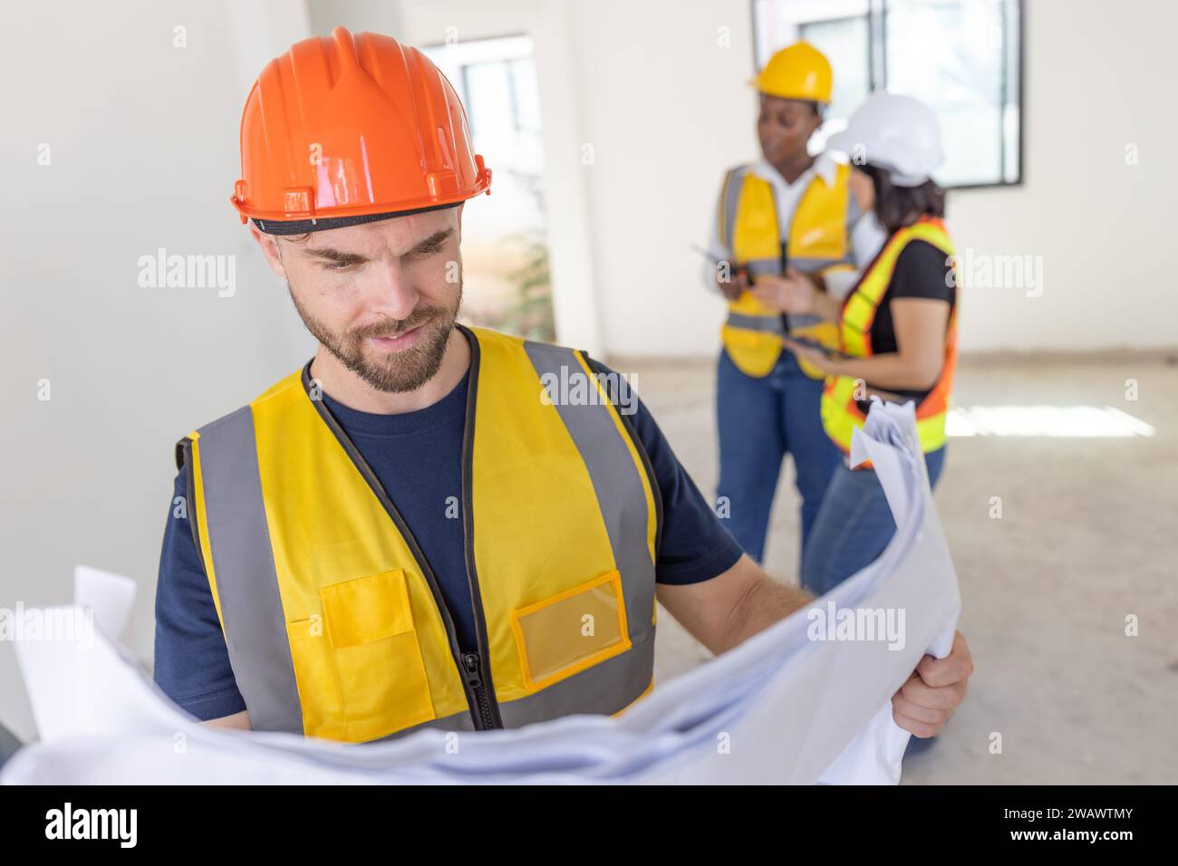 Ingegnere operaio edile professionista maschio. Costruttore di case immobiliari. Architetto intelligente che lavora in piedi in cantiere. Foto Stock