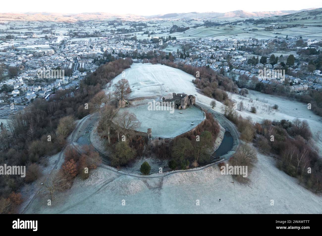 Kendal, Cumbria, 7 gennaio 2024 - Una notte di nebbia e temperature sotto lo zero ha portato una bella gelata mattutina alla città di Kendal in Cumbria domenica. Il castello di Kendal, che si affaccia sulla città medievale, era circondato da uno strato di ghiaccio bianco mentre gli escursionisti si godevano la vista. Le case ai piedi del castello sono sagomate in cerchi e gli ovali catturano anche il gelo. Credito: Stop Press Media/Alamy Live News Foto Stock