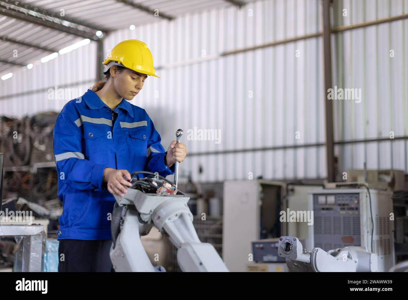 Tecnici meccanici addetti alla riparazione di riparazioni in sostituzione di parti rotte vecchie macchine a braccio robotico in officina. Foto Stock