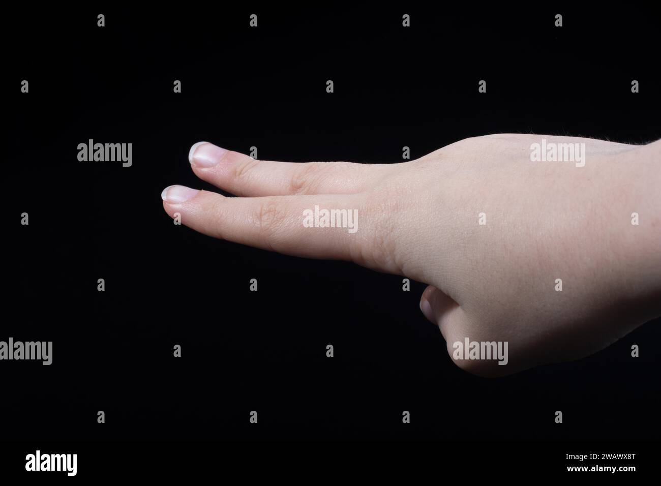 Due dita di una mano del bambino in parte visibile in sfondo nero Foto Stock