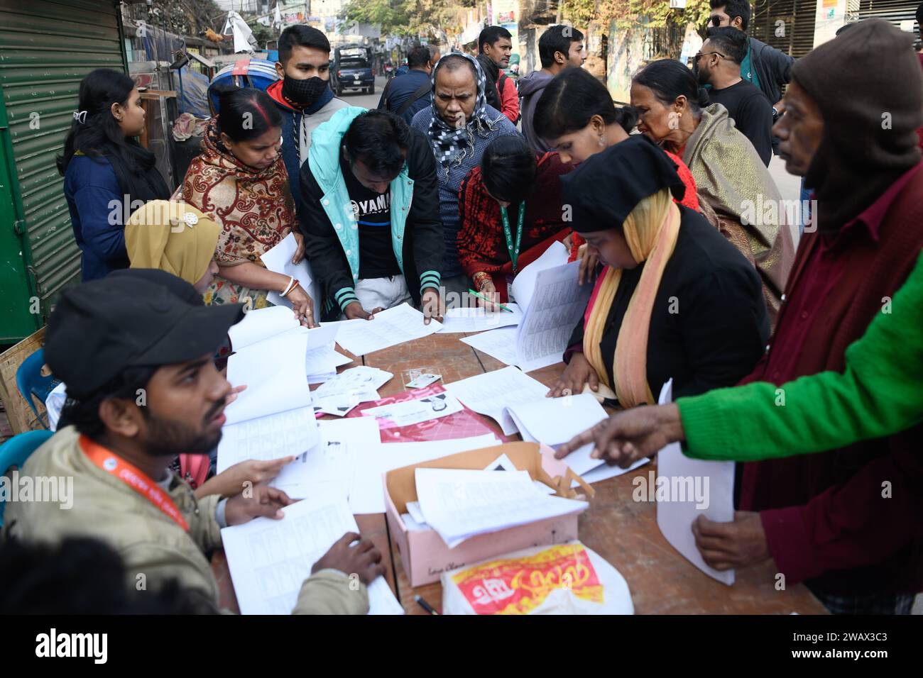 Dhaka, Bangladesh. 7 gennaio 2024. Gli agenti elettorali aiutano gli elettori a ottenere le loro liste di voto di fronte al centro di voto della Kamrunnessa Government Girls High School durante le 12 elezioni generali a Dacca. Credito: SOPA Images Limited/Alamy Live News Foto Stock