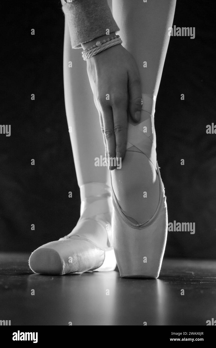 dettaglio dei piedi della ballerina di balletto femminile in posizione di balletto con scarpa pointe davanti a sfondo scuro Foto Stock