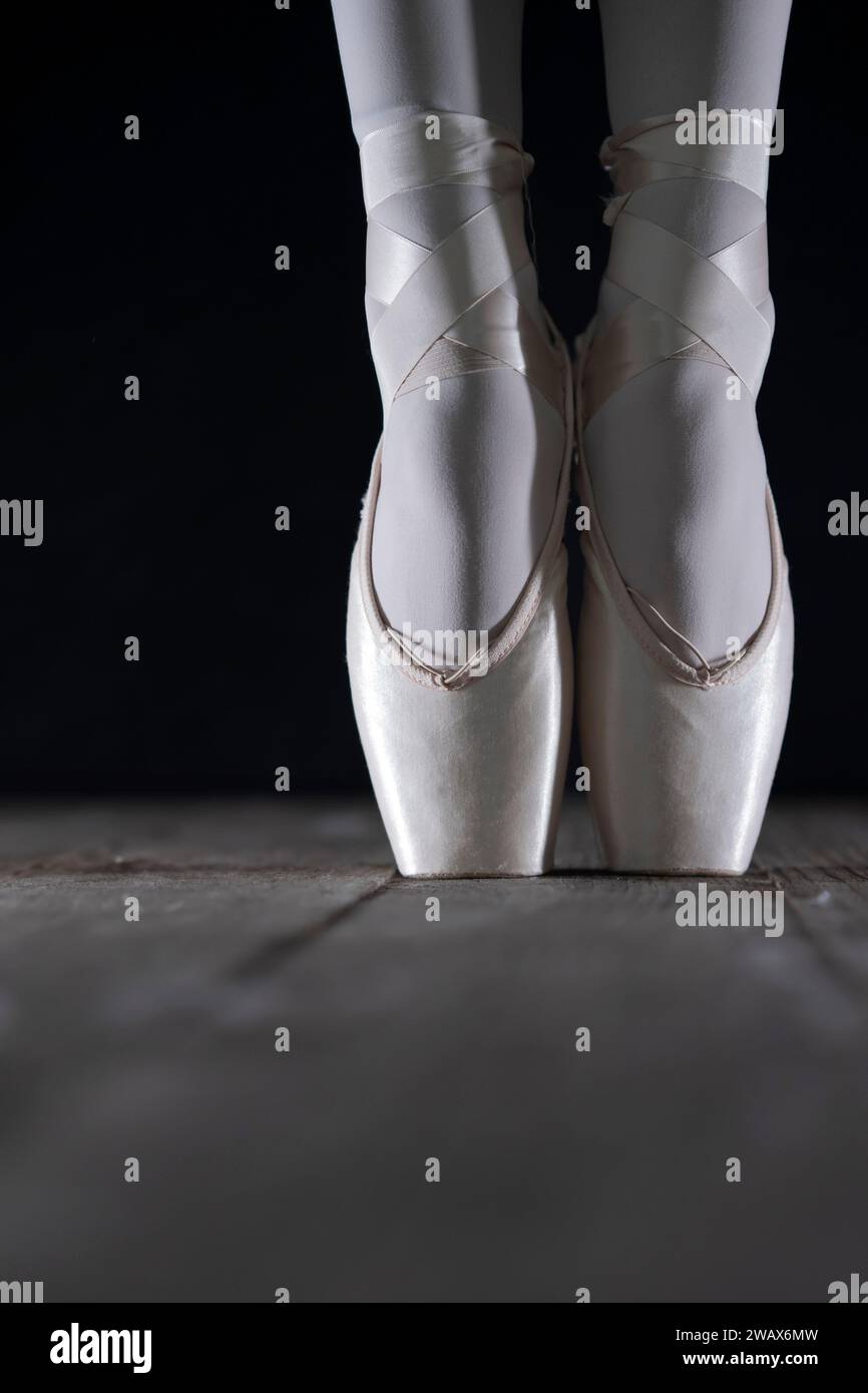 dettaglio dei piedi della ballerina di balletto femminile in posizione di balletto con scarpa pointe davanti a sfondo scuro Foto Stock
