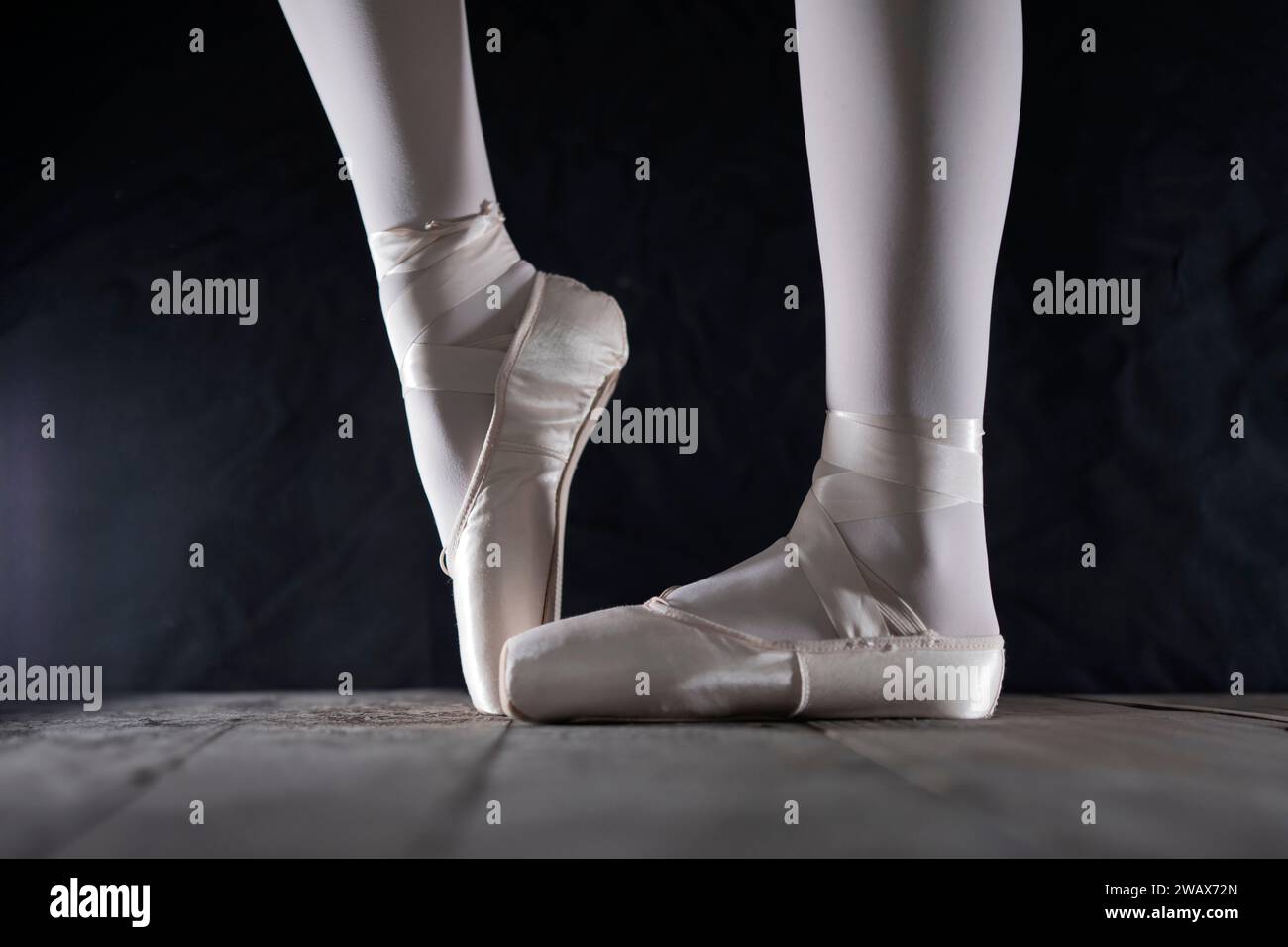 dettaglio dei piedi della ballerina di balletto femminile in posizione di balletto con scarpa pointe davanti a sfondo scuro Foto Stock